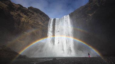 Tourist adlı Skogafoss şelale ile Çift gökkuşağı altında mavi gökyüzü, İzlanda