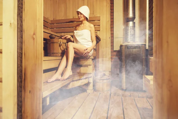 Jovem mulher bonita relaxante na sauna finlandesa envolto. Interior da sauna finlandesa, sauna clássica de madeira, relaxe na sauna quente — Fotografia de Stock