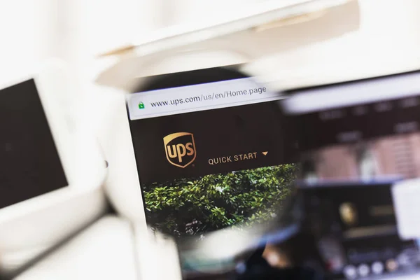 Los Angeles, California, USA - 27 February 2019: United Parcel Service official website homepage under magnifying glass. Concept United Parcel Service logo visible on smartphone, tablet screen, — Stock Photo, Image