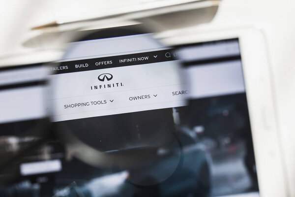 Nishi-ku, Yokohama, Japan - 14 March 2019: Infiniti Motor Company, car, official website homepage under magnifying glass. Concept Infiniti Motor Company, Car logo visible on smartphone, tablet screen,