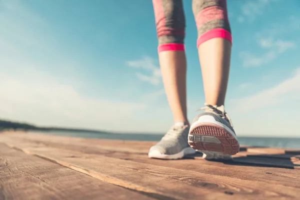 Legs in sneakers close-up. Health and Yoga Concept. Rear view close up strong athletic female legs and running shoes of sport. Sporty young girl practicing yoga. Woman do gymnastics outdoors