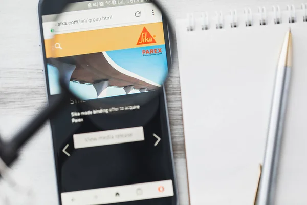 Los Angeles, California, USA - 3 April 2019: Sika Group official website homepage under magnifying glass. Concept Sika AG is a specialty chemical company logo visible on smartphone, tablet screen — Stock Photo, Image