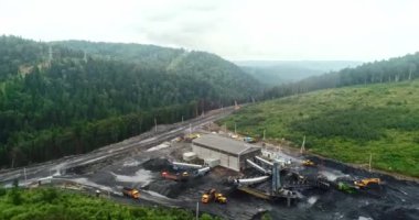 Açık maden ocağının yukarısından, üreme sıralaması, madencilik kömürü, çıkarma endüstrisi. Hareket halindeki şerit taşıyıcıdan kömür madenindeki kömür yığınına dökülen kömür madencileri arka planda çalışıyor..