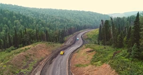 Panorama aerial view on road in forest. Aerial view of Dumpers on country road in forest. View from the drone at Taiga with lots of machinery trucks — Stock Video