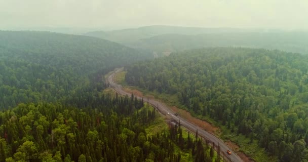 Panorama antény na silnici v lese. Letecký pohled na Dumpers na venkovské silnici v lese. Pohled z dronu v Taiga se spoustou strojních zařízení — Stock video