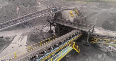 Açık maden ocağının yukarısından, üreme sıralaması, madencilik kömürü, çıkarma endüstrisi. Hareket halindeki şerit taşıyıcıdan kömür madenindeki kömür yığınına dökülen kömür madencileri arka planda çalışıyor..