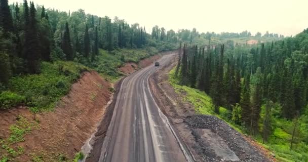 Панорама вид с воздуха на дорогу в лесу. Вид с воздуха на самосвалы на проселочной дороге в лесу. Вид с дрона на Тайгу с множеством механизированных грузовиков — стоковое видео