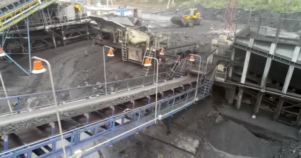 Сверху карьера, сортировка пород, добыча угля, добывающая промышленность. Вид сверху падающий уголь с транспортера движущейся ленты в кучу на угольной шахте с шахтерами, работающими на фоне. — стоковое видео