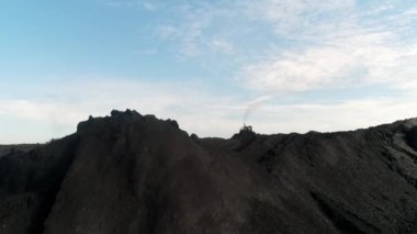 Buldozer kömür itiyor. Ekskavatör kömür üttürer. Çıkarıcı endüstri antrasit. Kömür endüstrisi. Bitmiş ürünlerle depo, zenginleştirilmiş kömür. Demet sert kömür