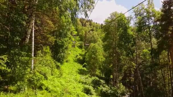 Panorama vista aérea em ropeway. Elevador de cadeiras na floresta. Movimento em Cableway no verão através da floresta. Movendo o funicular para a montanha — Vídeo de Stock