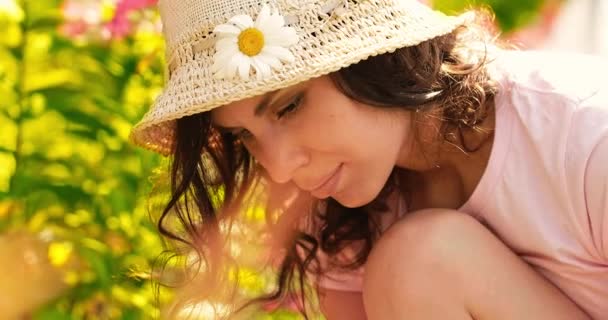 Mujer joven verano en el jardín cuida de flores, plantas. La chica de la granja se dedica a plantar. Mujer planta flores. Persona que trabaja en el jardín regando flores — Vídeos de Stock