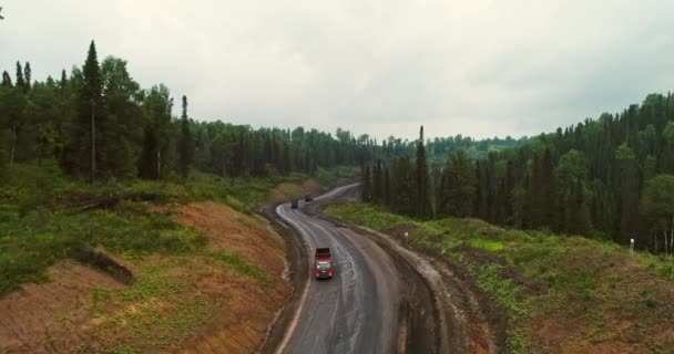 Panorama vista aérea sobre carretera en bosque. Vista aérea de los vertederos en la carretera del campo en el bosque. Vista desde el dron en Taiga con muchos camiones de maquinaria — Vídeo de stock