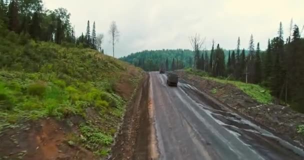 숲에서 도로에 파노라마 공중 보기입니다. 숲에서 시골 길에 덤퍼의 공중 보기입니다. 기계 트럭이 많은 타이가의 드론에서 바라볼 수 있습니다. — 비디오