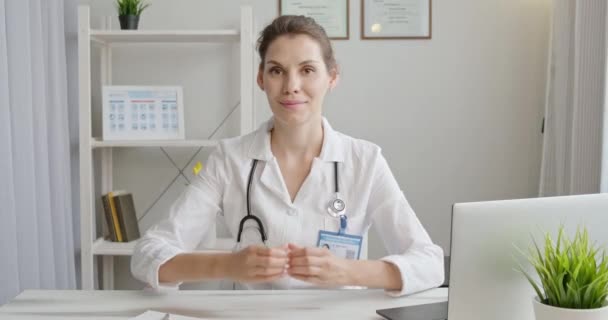 O médico mostra coração. Terapeuta faz gestos de mão coisas que eu te amo. Mulher de casaco médico mostra gesto cardíaco. Conceito de serviços de saúde remotos de telemedicina — Vídeo de Stock