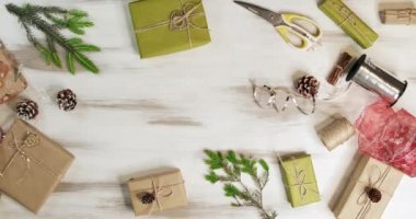 Üst manzara, Noel süsleri, hediyeler, yılbaşı ağacı üzerine yeni yıl masa planları yazan kız, ahşap masanın üzerinde yavaşça hareket ediyor. Noel ve yeni yıl konsepti