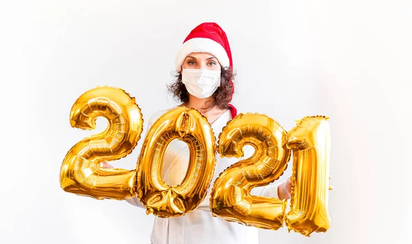 Nouvel An 2021 nombre d'or ballons Covid-19. Belle femme au Nouvel An avec casquette rouge. Fille souriante à la célébration. Concepts mode de vie des jeunes dans le masque médical — Photo