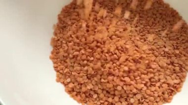 Bir sürü kırmızı mercimek ya da mazoor dal izole edilmiş beyaz arka planda üstten dökülüyor.