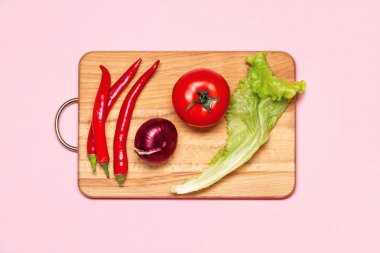 Üç taze kırmızı biber biber bir domates, yeşil salata ve menekşe yay