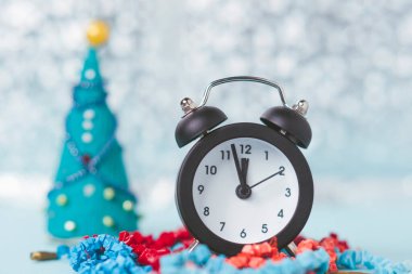 Yeni yılın Bokeh 'inin arka planında klasik çalar saat var. Oyuncak bir Noel ağacı arka planda odak dışı.