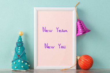 Yeni yıl çerçevesinde motivasyon amaçlı yeni yıl alıntısı. Çerçevenin her iki tarafında ve çerçevenin üzerinde Noel oyuncakları var..