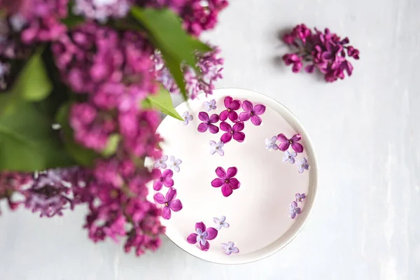 Five-pointed lilac flower among lilac flowers in a cup with water. Spa ritual. Lilac branch with a flower with 5 petals.