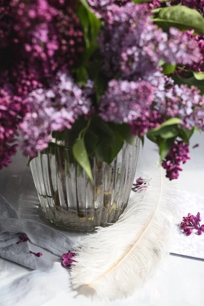 Bouquet of violet lilac in a glass vase. Still life with blooming branches of lilac in vases. Greeting card mock up.