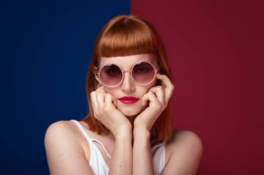 Güzel kızıl saçlı Genç kadın moda güneş gözlüğü takıyor portresi. Glamour makyaj kız. Saç kesimi ile saçak. 