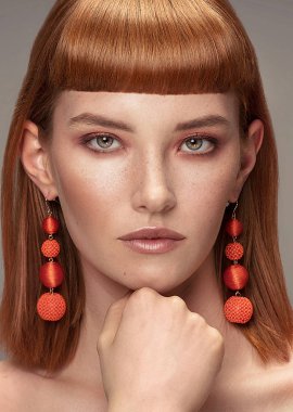 Kızıl saçlı Genç Bayan saçak, yüzündeki çiller ile güzellik portresi. Şık küpeler kız kameraya.