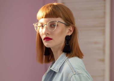 Saçak ve glamour makyaj pembe arka plan üzerinde poz ile moda Kızıl saçlı Bayan kameraya arıyorum.