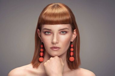 Kızıl saçlı Genç Bayan saçak, yüzündeki çiller ile güzellik portresi. Şık küpeler kız kameraya.