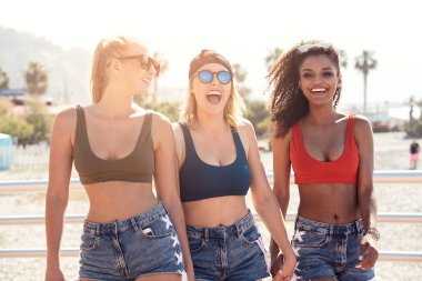 Birlikte eğleniyor Üç güzel çok etnik gülümseyen kız. Güneşli yaz günü İtalyan sahilinde. Uygun organları moda güneş gözlüğü ve kısa kot giyen kadınlarla grup. Tatil zamanı.