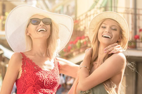 Happy female wears summer hat and fashionable dress spends recreation time with best friend, walk on italian city streets,smiling. Summer sunny day.