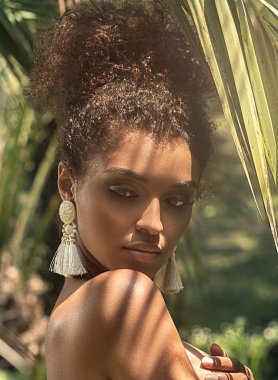 Palm üzerinde poz tek küpe, giyen güzel Afrikalı-Amerikalı kadın tropikal sürgün bırakır.