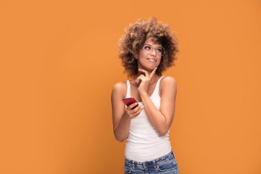 Cep telefonu, sarı arka plan üzerinde ayakta tutan bir gülümseyen güzel Afrikalı kadın fotoğrafı ile afro saç modeli,.