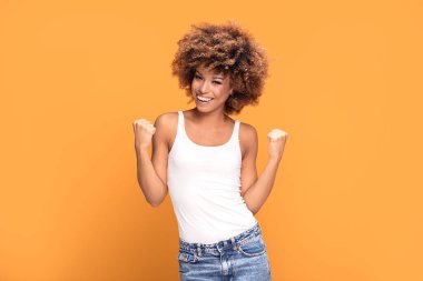 Ne başarı ama! Zaferini kutluyor, sarı arka plan üzerinde poz güzel mutlu Afrikalı-Amerikalı kadın. Olumlu duygular.
