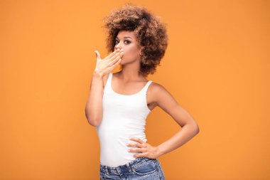 Sürpriz hayran güzel afro kadın kameraya, seyir gülümseyerek. Sarı arka plan üzerinde poz kız.