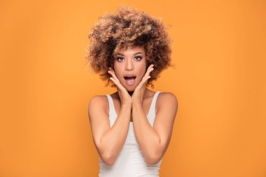 Geniş açık ağızlı kameraya, seyir sürpriz hayran güzel afro kadın gülümsüyor. Sarı arka plan üzerinde poz kız.