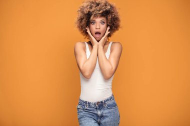 Geniş açık ağızlı kameraya bakarak hayran güzel afro kadın şaşırttı. Şok kız sarı arka plan üzerinde poz.