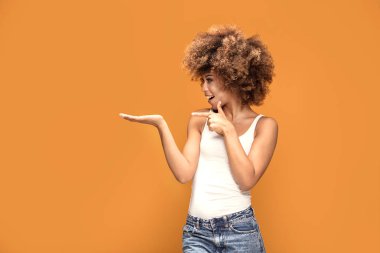 Boş el altında sarı arka plan üzerinde renkli fotoğraf gülümseyen güzel Afrikalı-Amerikalı kadın, puan onun parmak.