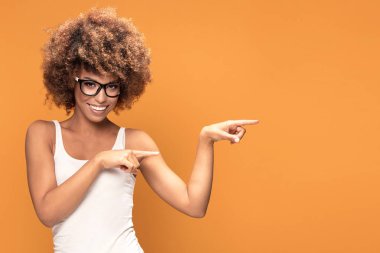 Renkli fotoğraf gülümseyen güzel Afrikalı-Amerikalı kadın, parmaklarını sarı arka plan puan..