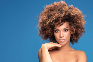 Glamour makyaj ve afro saç modeli ile Afrikalı-Amerikalı kadın güzellik portresi. Mavi arka plan üzerinde poz kız kameraya,.