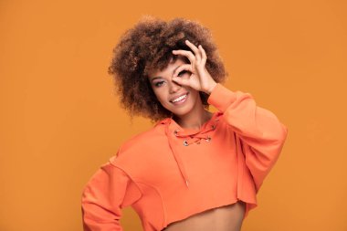 Gülümseyen güzel genç Afro-Amerikan kadın kıvırcık afro saçlı kameraya, sarı arka planı arıyorum.