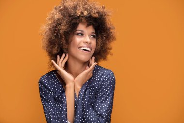Gülümseyen güzel Afrikalı-Amerikalı genç kadın portresi. Afro saç modeli olan kız. Sarı arka plan. Stüdyo vurdu.