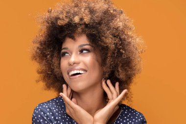 Gülümseyen güzel Afrikalı-Amerikalı genç kadın portresi. Afro saç modeli olan kız. Sarı arka plan. Stüdyo vurdu.