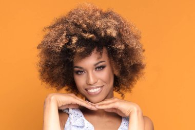 Sarı arka plan üzerinde poz afro saç modeli ile gülümseyen Afrikalı-Amerikalı genç kadın güzellik portresi.