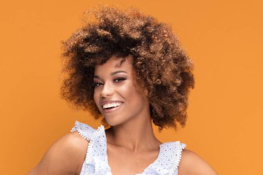 Sarı arka plan üzerinde poz afro saç modeli ile gülümseyen Afrikalı-Amerikalı genç kadın güzellik portresi.