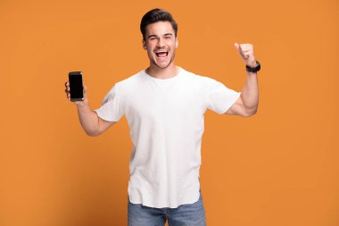 Cep telefonu sarı stüdyo arka plan üzerinde poz tutan adam yakışıklı gülümseyen heyecan.