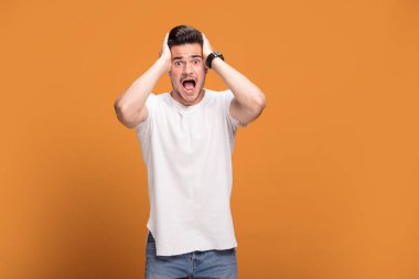 Kameraya, sarı stüdyo arka plan üzerinde poz arayan genç yakışıklı adam onun başarı zevk gülümseyen.