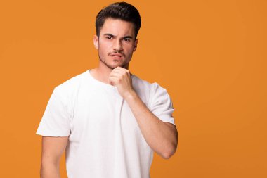 Düşünme, sarı stüdyo arka plan üzerinde duran yakışıklı genç adam. Duygusal yüz ifadesi.