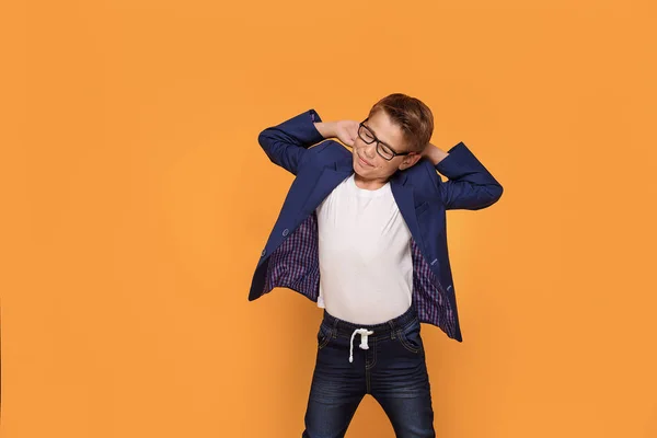 微笑快乐的小优雅的男孩摆在橙色工作室背景 穿着时髦的眼镜和夹克 — 图库照片